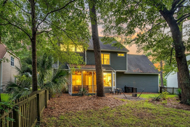 back house at dusk with central air condition unit and a patio area