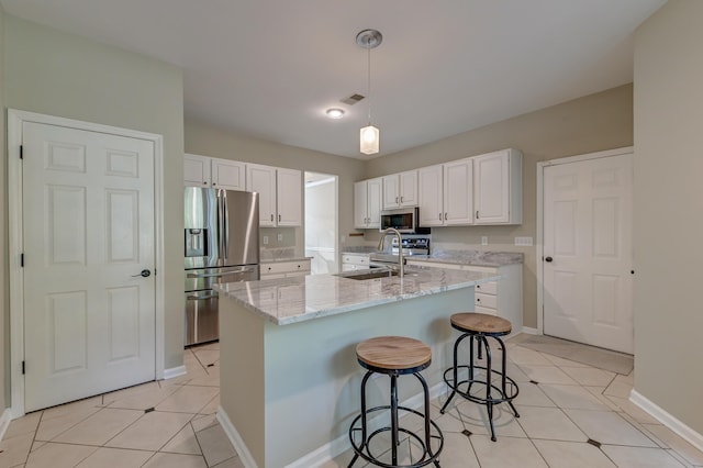 kitchen with white cabinetry, sink, stainless steel appliances, an island with sink, and a breakfast bar