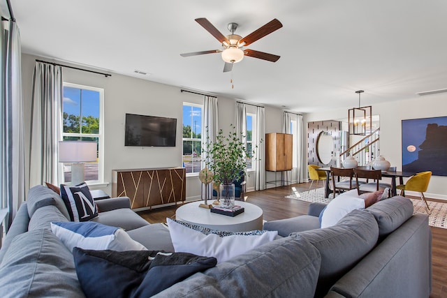 living room with dark wood-type flooring and ceiling fan with notable chandelier