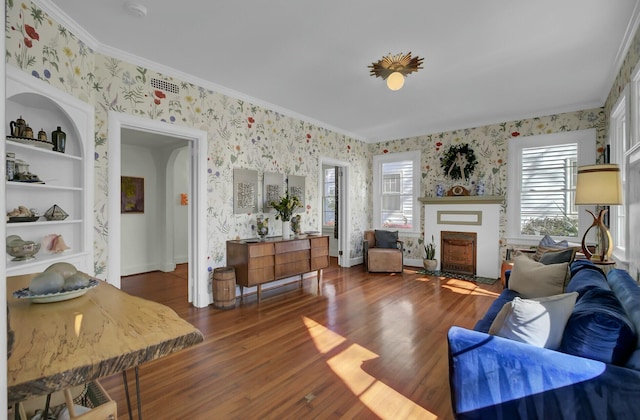 living room featuring crown molding, built in shelves, and dark hardwood / wood-style floors