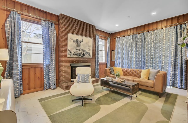 living area with light tile patterned flooring, a fireplace, and wood walls