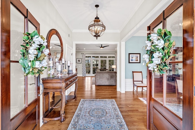 foyer entrance featuring ornamental molding, ceiling fan with notable chandelier, french doors, and wood finished floors