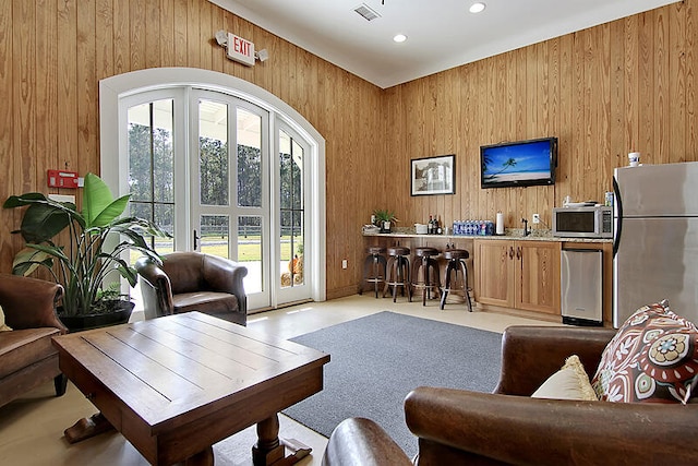 living room featuring indoor wet bar, recessed lighting, a healthy amount of sunlight, and wooden walls