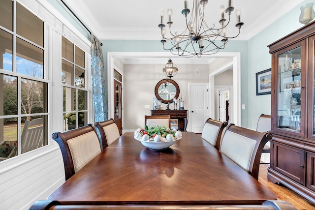 dining space with wood finished floors, crown molding, and an inviting chandelier