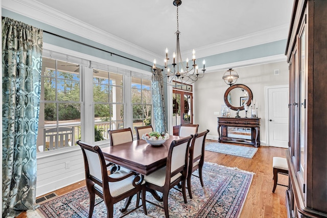 dining space with ornamental molding, visible vents, and light wood-style floors