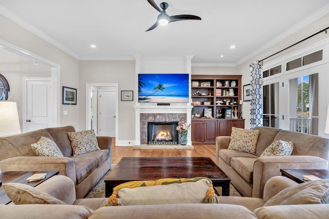 living area featuring ornamental molding, light wood-type flooring, a fireplace, and recessed lighting