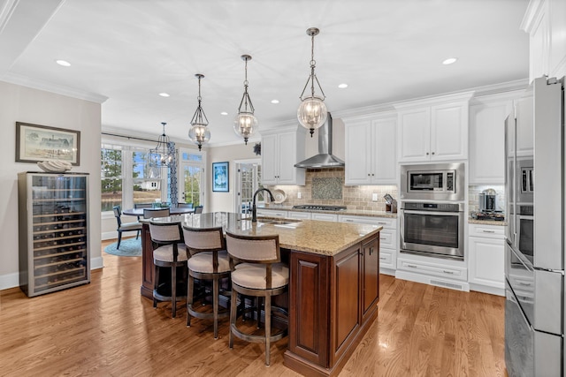 kitchen featuring beverage cooler, stainless steel appliances, a sink, wall chimney exhaust hood, and tasteful backsplash