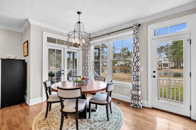 dining space with light wood-style floors, french doors, a healthy amount of sunlight, and crown molding