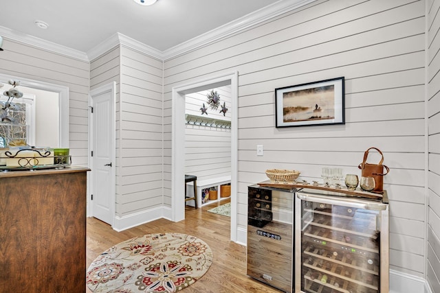 bar featuring light wood-type flooring, wine cooler, and crown molding