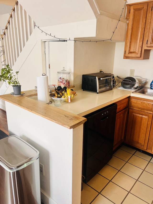 kitchen featuring black dishwasher, sink, and light tile patterned floors