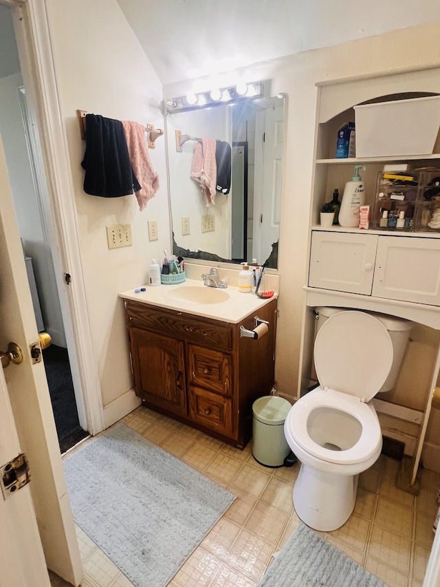 bathroom featuring vanity, toilet, and lofted ceiling