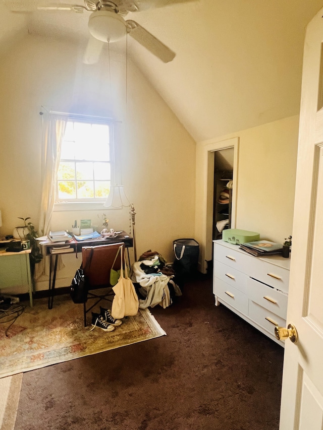 interior space with ceiling fan, vaulted ceiling, and dark colored carpet