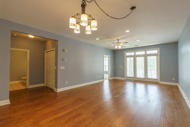 spare room featuring recessed lighting, baseboards, ceiling fan with notable chandelier, and wood finished floors