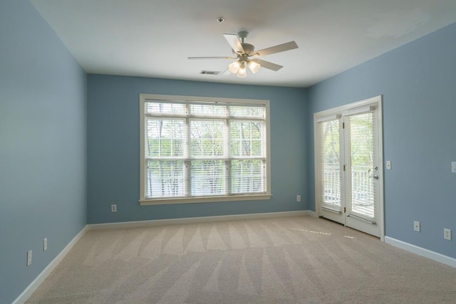 carpeted empty room featuring visible vents, ceiling fan, and baseboards