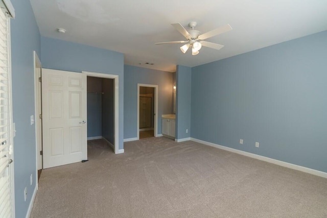 unfurnished bedroom with a spacious closet, baseboards, a closet, and light colored carpet