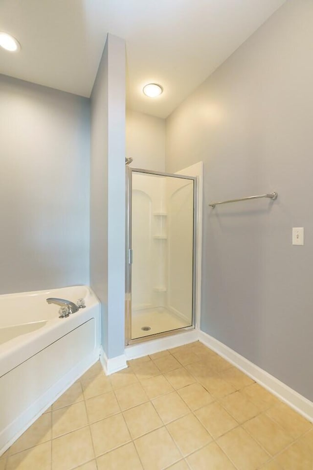 bathroom featuring a shower stall, tile patterned flooring, a bath, and baseboards