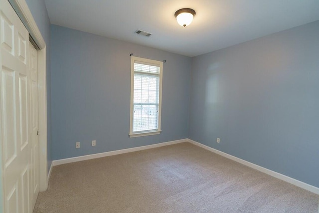 carpeted spare room with visible vents and baseboards