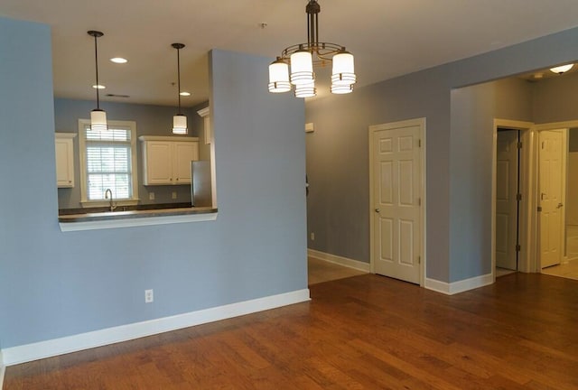 interior space with decorative light fixtures, baseboards, freestanding refrigerator, and wood finished floors