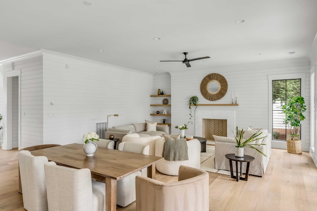 dining space featuring light wood-type flooring, ceiling fan, and wood walls