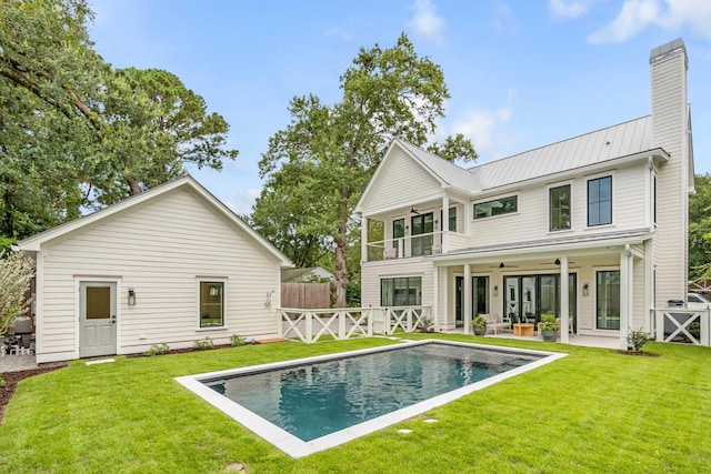 rear view of property with ceiling fan, a lawn, a balcony, and a patio