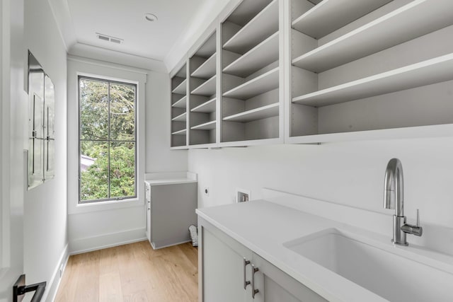 laundry area featuring cabinets, electric dryer hookup, light hardwood / wood-style floors, sink, and washer hookup