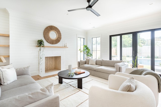 living room featuring ceiling fan, wood walls, french doors, and light wood-type flooring