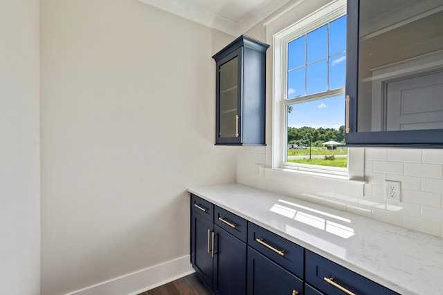 bar featuring light stone countertops, tasteful backsplash, crown molding, and dark wood-type flooring