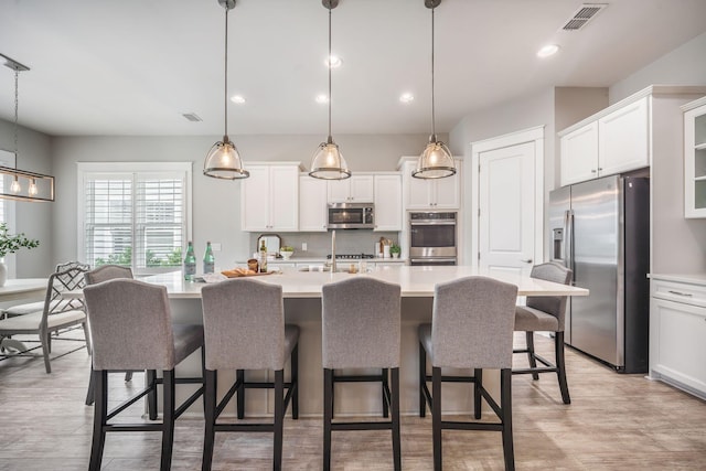331 Fish Creek Ct, Summerville, SC 29486 - kitchen with appliances with stainless steel finishes, light countertops, a breakfast bar area, an island with sink, and white cabinets
