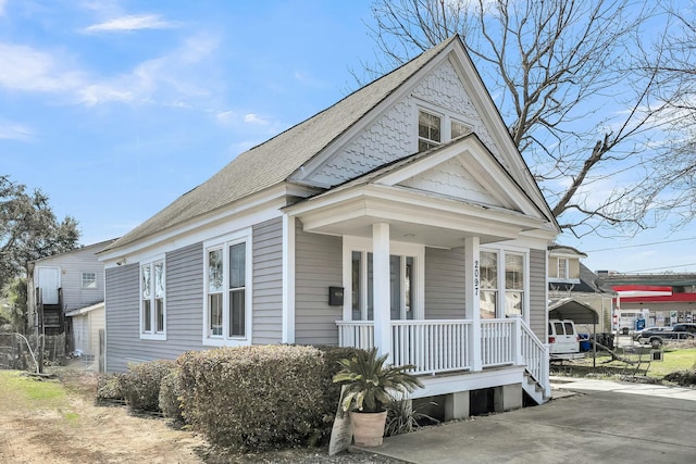 view of front facade with a porch, a shingled roof, and driveway