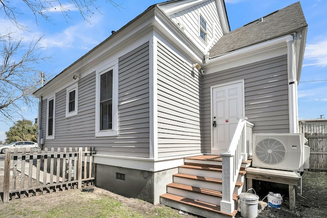 exterior space with ac unit, crawl space, a shingled roof, and fence