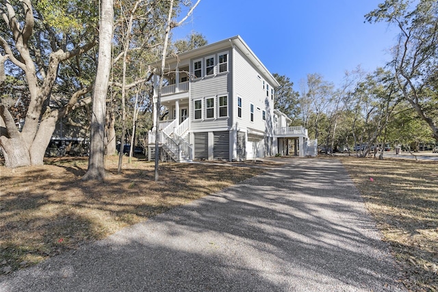 view of side of property featuring a balcony, a garage, and covered porch