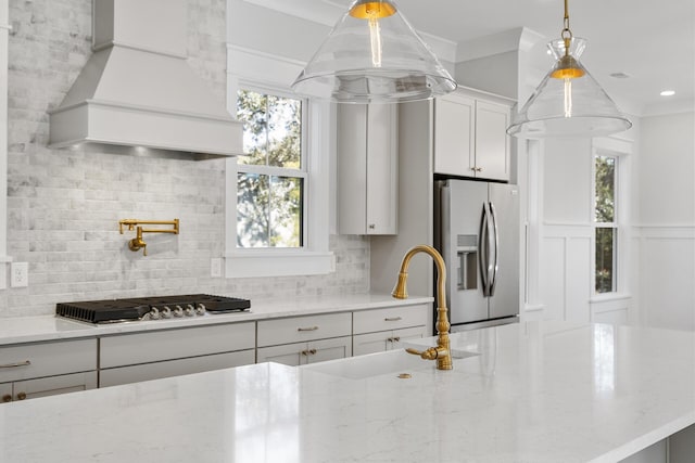 kitchen with premium range hood, sink, white cabinets, light stone counters, and stainless steel appliances