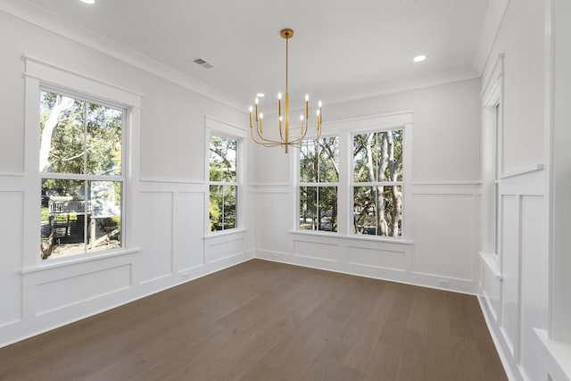 unfurnished dining area with an inviting chandelier, ornamental molding, and dark hardwood / wood-style flooring