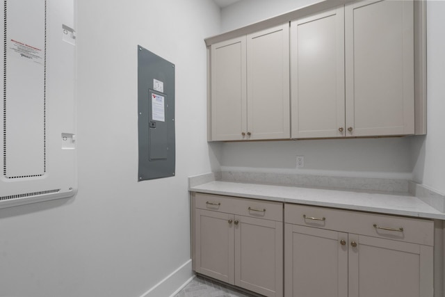 kitchen featuring light stone counters, gray cabinets, and electric panel