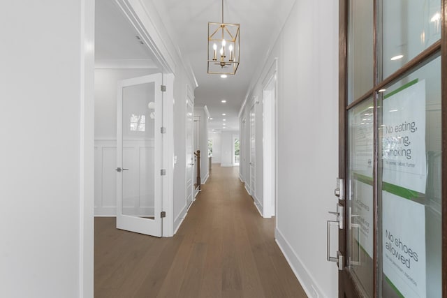 hallway featuring ornamental molding, dark hardwood / wood-style flooring, and a chandelier