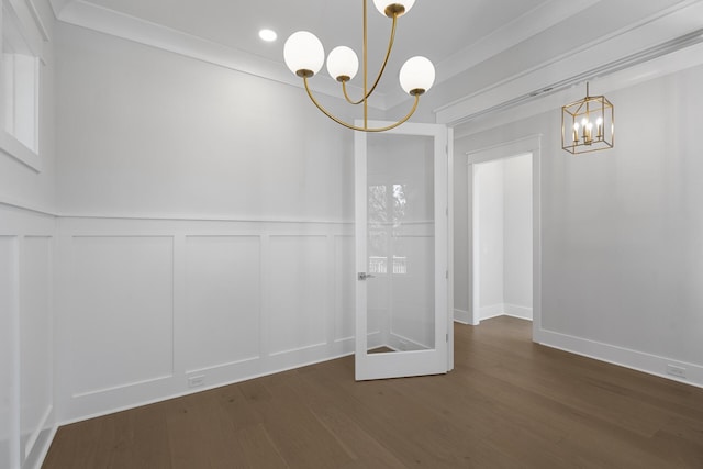 spare room with dark wood-type flooring, ornamental molding, and a chandelier