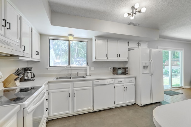 kitchen featuring sink, white appliances, light tile patterned floors, a textured ceiling, and white cabinets