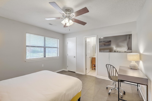 tiled bedroom featuring connected bathroom, ceiling fan, and a textured ceiling