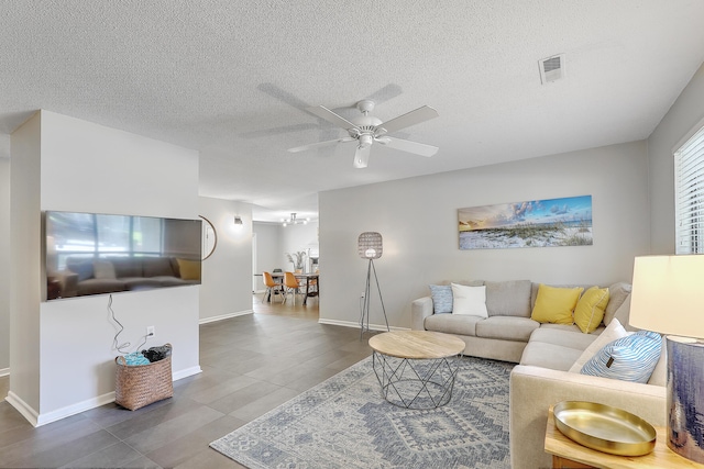 living room featuring tile patterned flooring, a textured ceiling, and ceiling fan