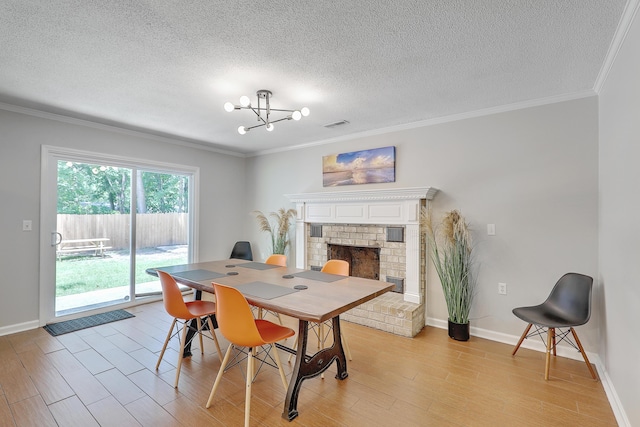 dining room featuring a notable chandelier, a fireplace, ornamental molding, and light wood-type flooring