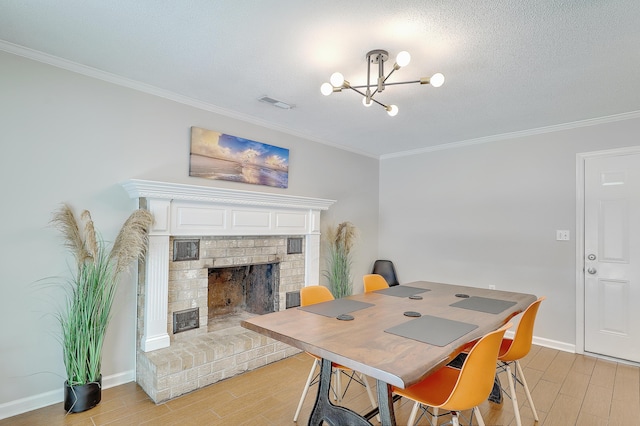 dining area featuring crown molding, a chandelier, a fireplace, and light wood-type flooring