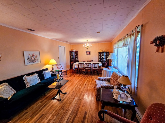 living room with an inviting chandelier, crown molding, and wood-type flooring