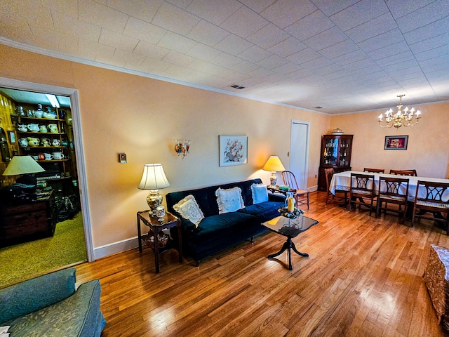 living room with wood-type flooring, a notable chandelier, and ornamental molding