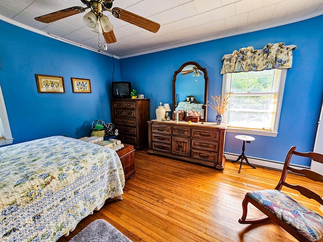 bedroom with baseboard heating, ceiling fan, hardwood / wood-style floors, and crown molding