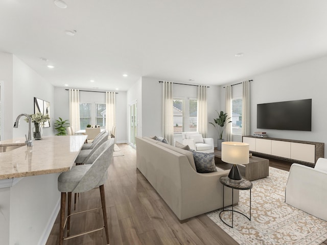 living room featuring light wood-type flooring, a healthy amount of sunlight, and sink