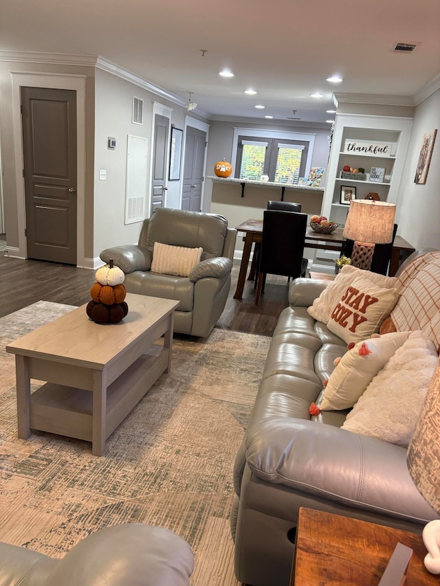 living room featuring dark wood-type flooring, crown molding, and built in features