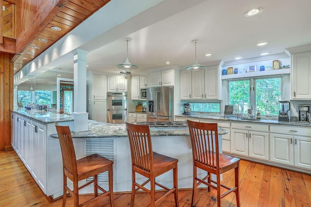 2287 Shoreline Dr, Johns Island, SC 29455 - kitchen with appliances with stainless steel finishes, white cabinets, light wood finished floors, light stone counters, and a kitchen breakfast bar