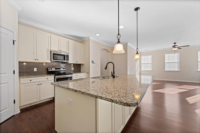 kitchen featuring an island with sink, stainless steel appliances, pendant lighting, light stone counters, and dark hardwood / wood-style floors