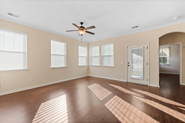 empty room with dark wood-type flooring, crown molding, and plenty of natural light