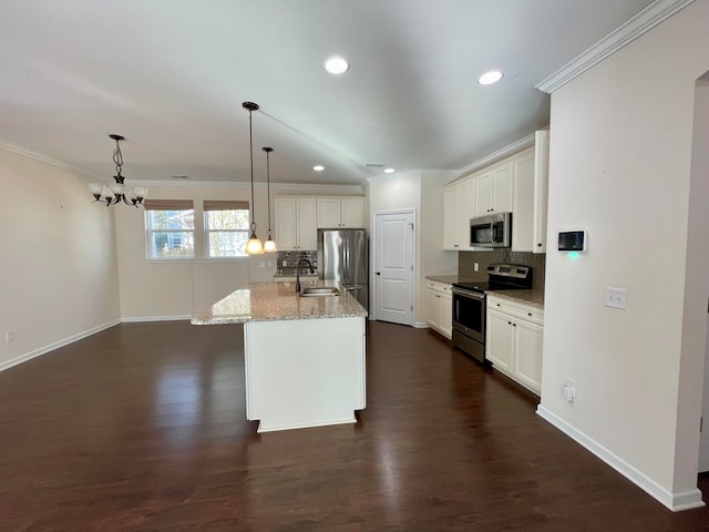 kitchen featuring appliances with stainless steel finishes, hanging light fixtures, dark wood-type flooring, light stone counters, and a kitchen island with sink